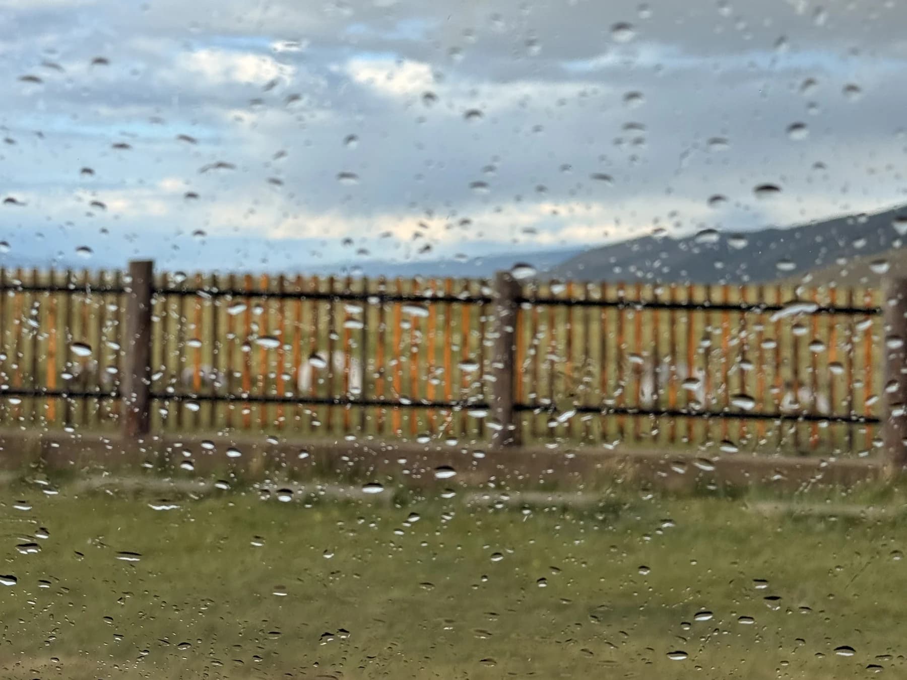 A countryside view through a rain-speckled window
